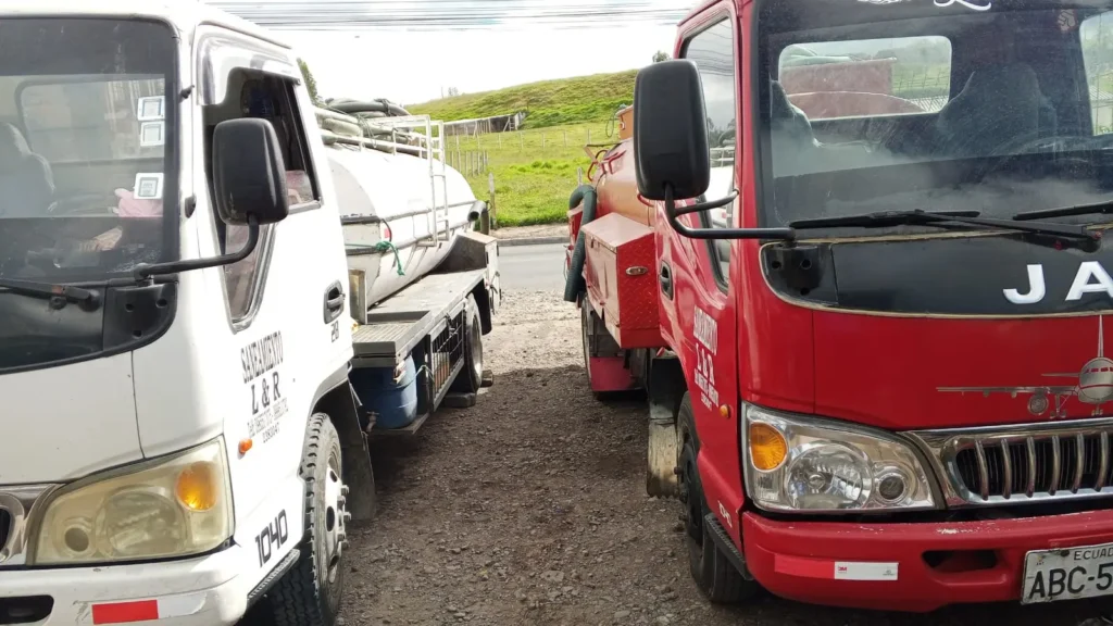 Camión cisterna junto a camioneta roja